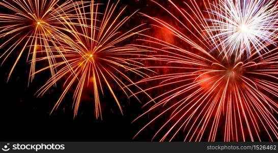 Red and yellow fireworks bursting on dark night sky background. Fireworks widescreen