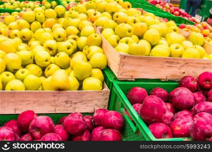 Red and yellow fresh apples in a wooden crates at farmers market