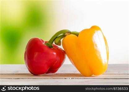 Red and yellow pepper on a wooden table in a garden