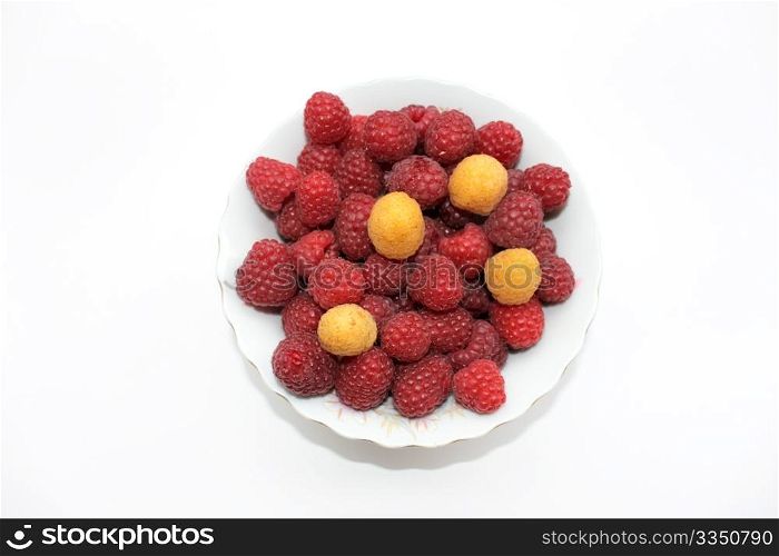 Red and yellow raspberries in the bowl, isolated