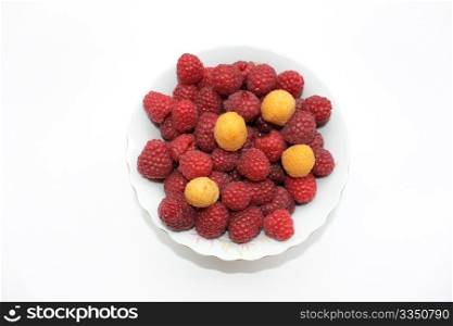 Red and yellow raspberries in the bowl, isolated
