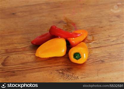 red and yellow ripe peppers lies on wooden cutting board