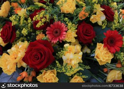red and yellow roses and yellow freesias in a flower arrangement