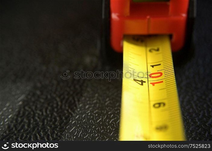 Red and yellow tape measure on black.