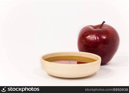Red apple and bowl of honey isolated on a white background. Symbols of Jewish New Year - Rosh Hashanah.