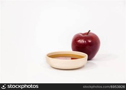 Red apple and bowl of honey isolated on a white background. Symbols of Jewish New Year - Rosh Hashanah.