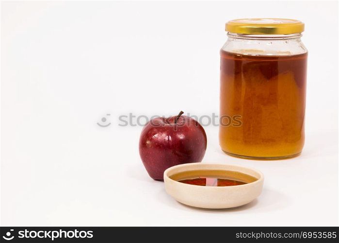 Red apple and jar of honey bowl of honey isolated on a white background. Symbols of Jewish New Year - Rosh Hashanah.