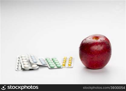 Red apple and pills blister. Red apple and colorful pills in blister on white background