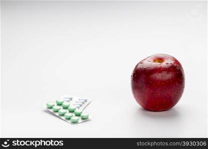 Red apple and pills blister. Red apple and colorful pills in blister on white background