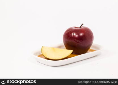 Red apple and red apple slice on white plate with honey isolated on a white background. Symbols of Jewish New Year - Rosh Hashanah.