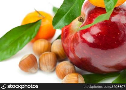 red apple, mandarin with green leaves and nuts isolated on white