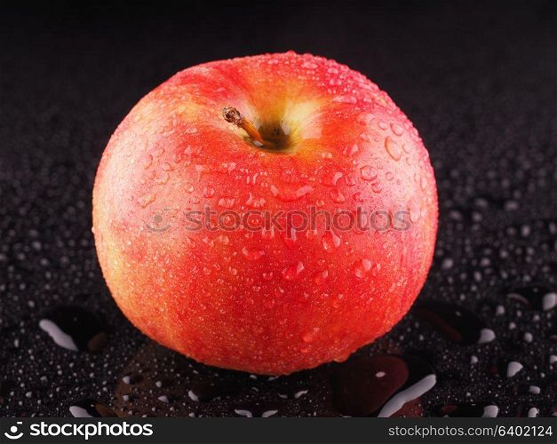 Red apple on a dark background with droplets