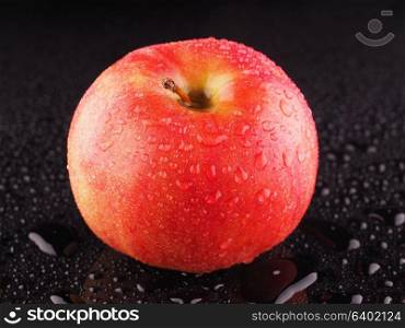 Red apple on a dark background with droplets