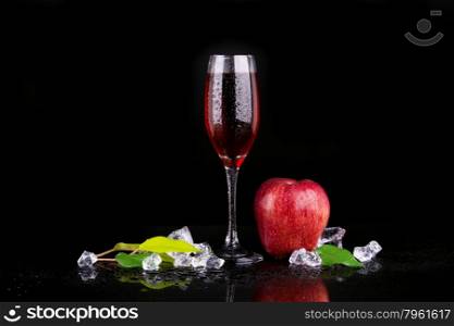 Red apple with a glass of champagne on black background