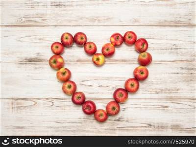 Red apples heart over rustic wooden background. Love concept