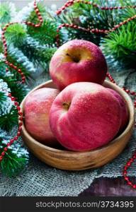 Red apples in wooden bowl with festive decorations, selective focus