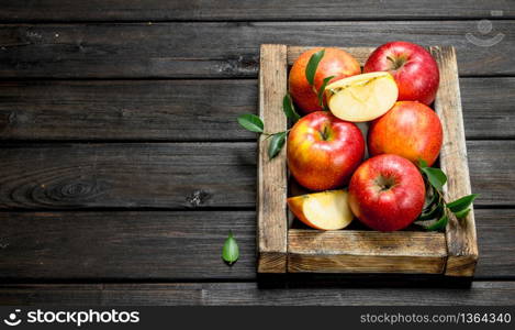 Red apples with leaves and Apple slices in a wooden box. On a dark wooden background.. Red apples with leaves and Apple slices in a wooden box.