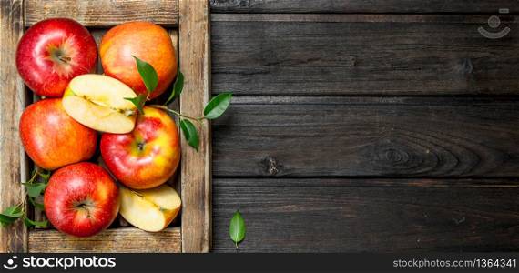 Red apples with leaves and Apple slices in a wooden box. On a dark wooden background.. Red apples with leaves and Apple slices in a wooden box.