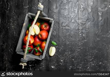 Red apples with leaves and Apple slices in a wooden box. On a dark wooden background.. Red apples with leaves and Apple slices in a wooden box.