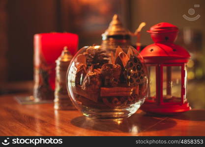 Red aromatic candle with coffee beans and orange slices on a glass stand. Handmade aroma glass