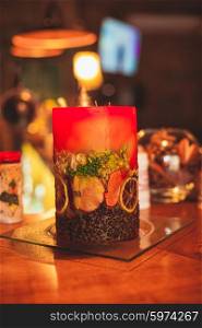 Red aromatic candle with coffee beans and orange slices on a glass stand. Handmade winter bar