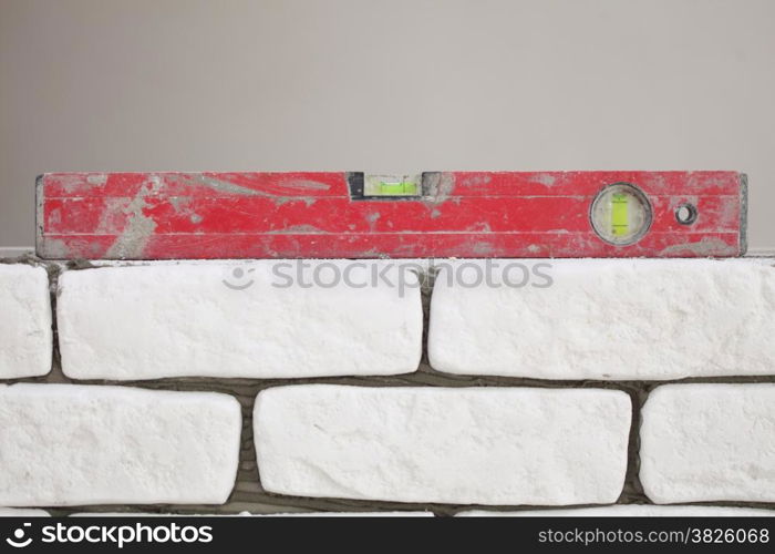 Red balance spirit building level in construction site. Check the level of a brick house wall