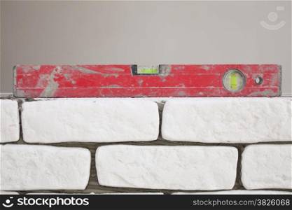 Red balance spirit building level in construction site. Check the level of a brick house wall