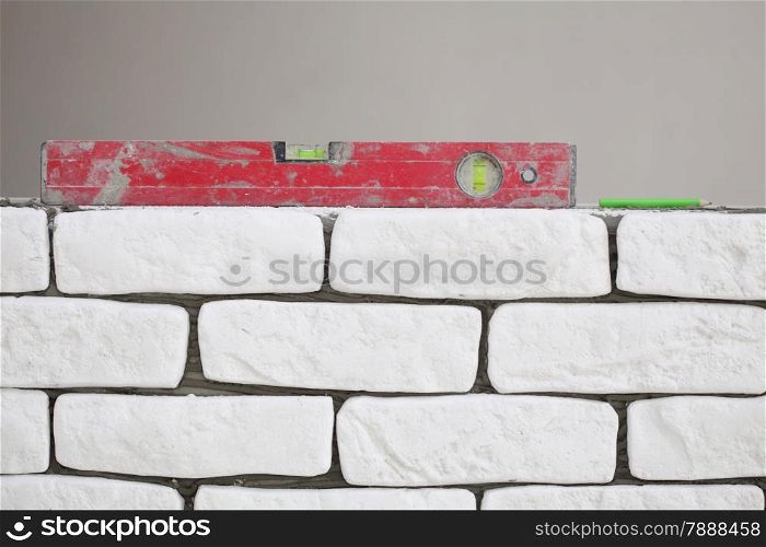 Red balance spirit building level in construction site. Check the level of a brick house wall