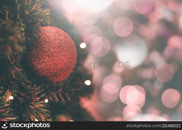 Red balls on the Christmas tree with pink-red backdrop for celebrations.