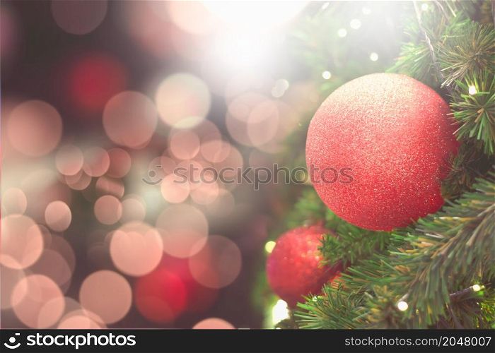 Red balls on the Christmas tree with pink-red backdrop for celebrations.