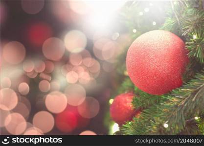 Red balls on the Christmas tree with pink-red backdrop for celebrations.