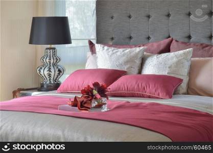 red bed and pillows with plant in glass vase on tray in bedroom