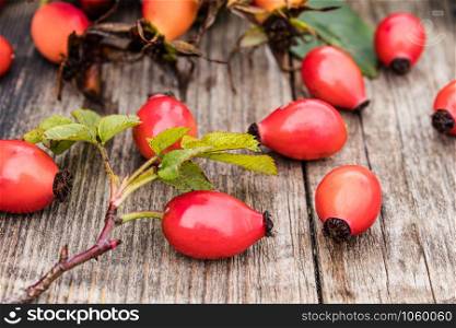 Red berries and rosehip leaves on a wooden table. Close-up.. Red berries and rosehip leaves on a wooden table. C