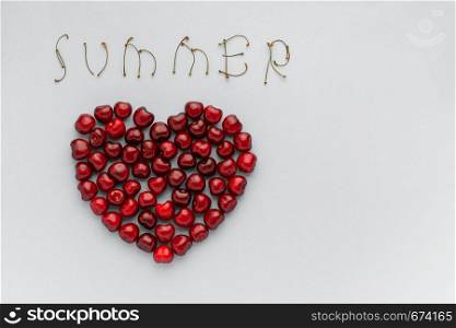 Red berry cherries in shape of heart and text SUMMER, Still life on blue background. Flat lay, Top view. Copy space Concept - love of cherry and summer. Red berry cherries in shape of heart and text SUMMER, Still life on blue background. Flat lay, Top view. Copy space Concept
