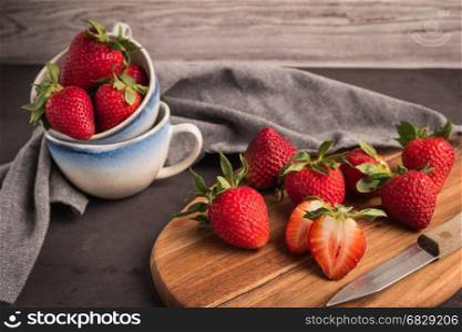 Red berry strawberry in ceramic mugs on old concrete background. Background from freshly harvested strawberries