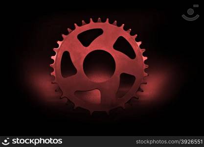 Red bicycle chainring on a black background.