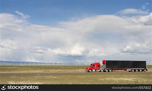 Red big rig semit truck with black cargo trailer on a Utah Highway