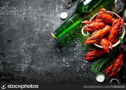 Red boiled crayfish in a bowl with beer in a bottle and dill. On dark rustic background. Red boiled crayfish in a bowl with beer in a bottle and dill.