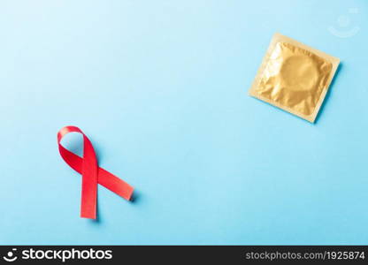 Red bow ribbon symbol HIV, AIDS cancer awareness and condom with shadows, studio shot isolated on blue background, Healthcare medicine sexually concept, World AIDS Day