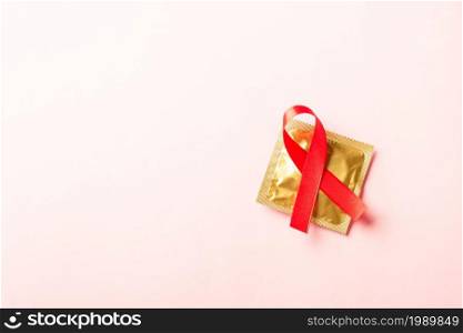 Red bow ribbon symbol HIV, AIDS cancer awareness and condom with shadows, studio shot isolated on pink background, Healthcare medicine sexually concept, World AIDS Day