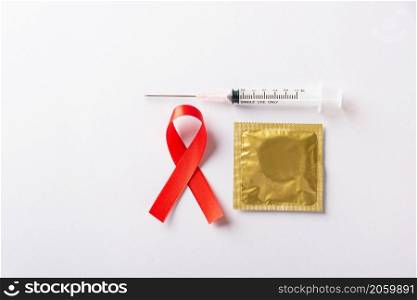 Red bow ribbon symbol HIV, AIDS cancer awareness, condom and syringe with shadows, studio shot isolated on white background, Healthcare medicine sexually concept, World AIDS Day