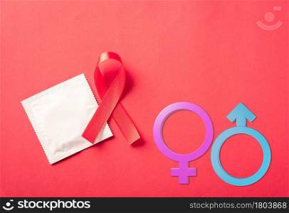 Red bow ribbon symbol HIV, AIDS cancer awareness, condom with shadows and Male, female gender signs, studio shot isolated on red background, Healthcare medicine sexually concept, World AIDS Day