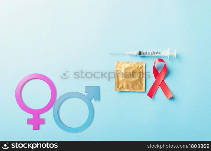 Red bow ribbon symbol HIV, AIDS cancer awareness, Male, female gender signs, condom and syringe, studio shot isolated on blue background, Healthcare medicine sexually concept, World AIDS Day