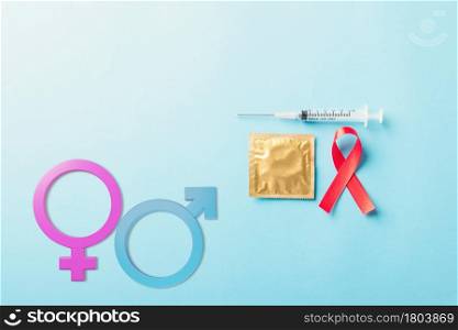 Red bow ribbon symbol HIV, AIDS cancer awareness, Male, female gender signs, condom and syringe, studio shot isolated on blue background, Healthcare medicine sexually concept, World AIDS Day