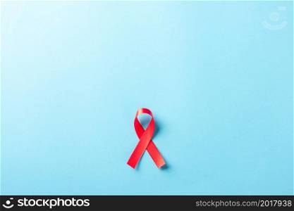 Red bow ribbon symbol HIV, AIDS cancer awareness with shadows, studio shot isolated on blue background, Healthcare medicine concept, World AIDS Day