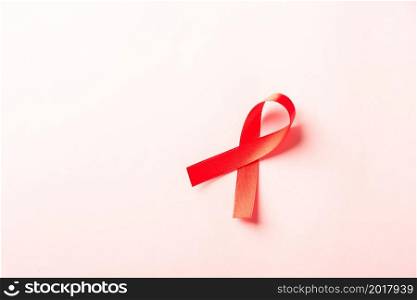 Red bow ribbon symbol HIV, AIDS cancer awareness with shadows, studio shot isolated on pink background, Healthcare medicine concept, World AIDS Day