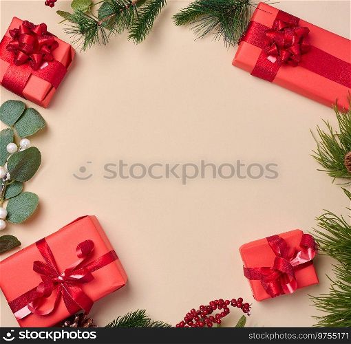 Red boxes with gifts, fir branches with Christmas decor on a beige background, erhu view. Copy space