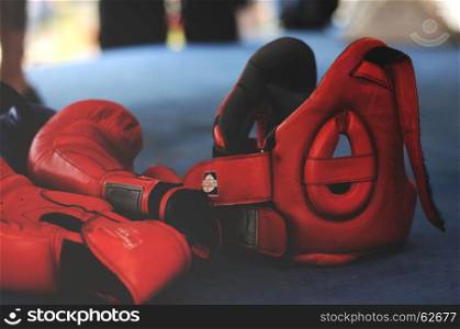 Red boxing gloves and headgear on boxing ring.