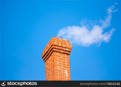 Red brick chimney releasing white smoke on clear blue sky.