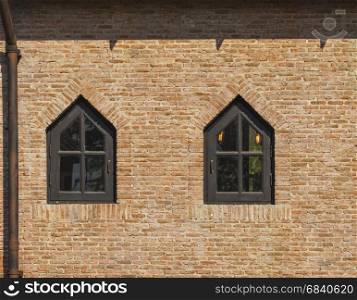 red brick wall and dark brown painted wood window (triangle shape)